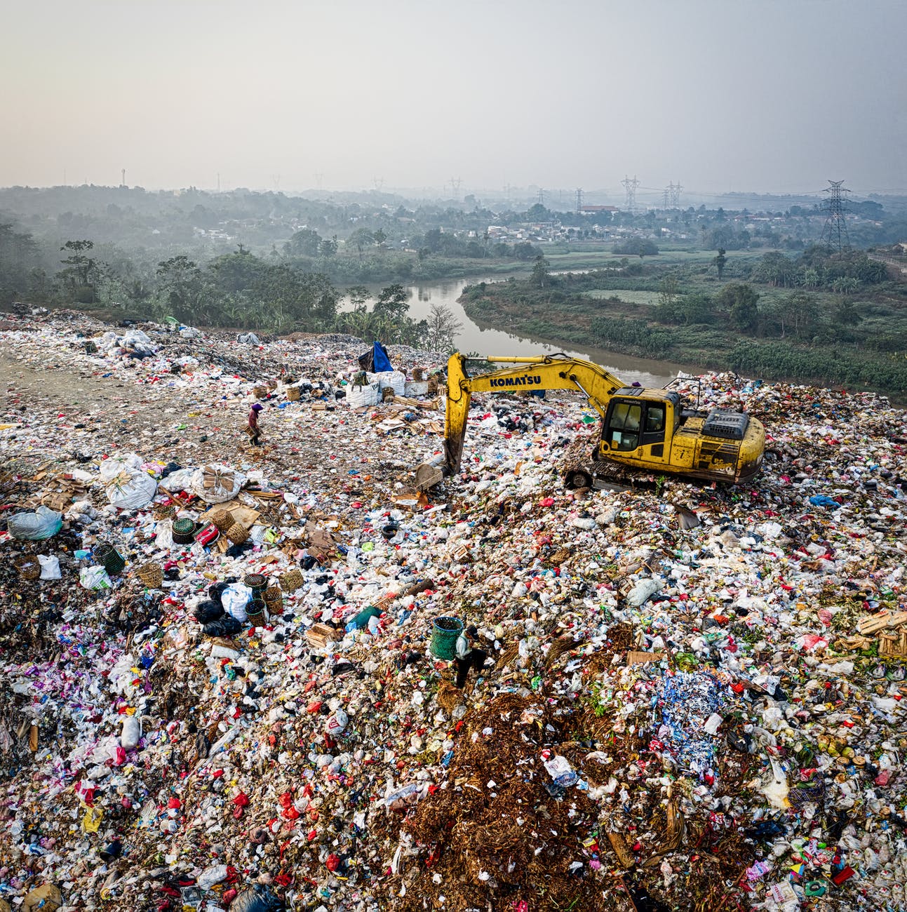 yellow excavator on piles of trash